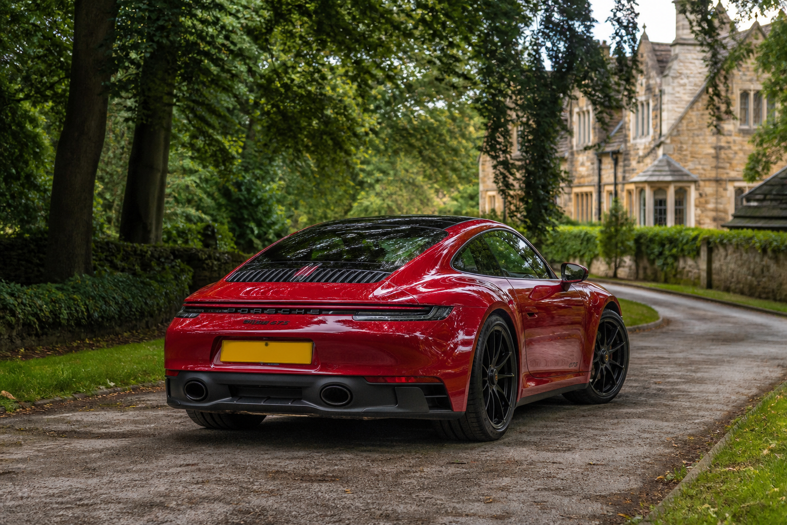 Carmine Red Porsche 911 Carrera 4 GTS on a private country lane